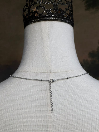 A mannequin wearing a historical jewelry inspired vintage style daisy flower pendant necklace with pearl dangle in silver toned stainless steel