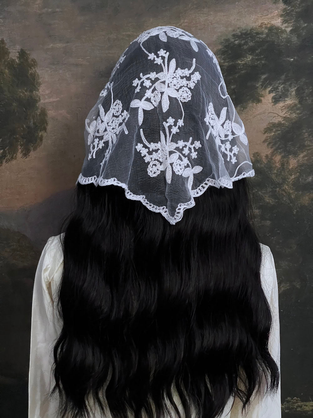 Mannequin wearing a vintage style white lace headscarf babushka triangle headdress made from floral embroidery lace against an art history background