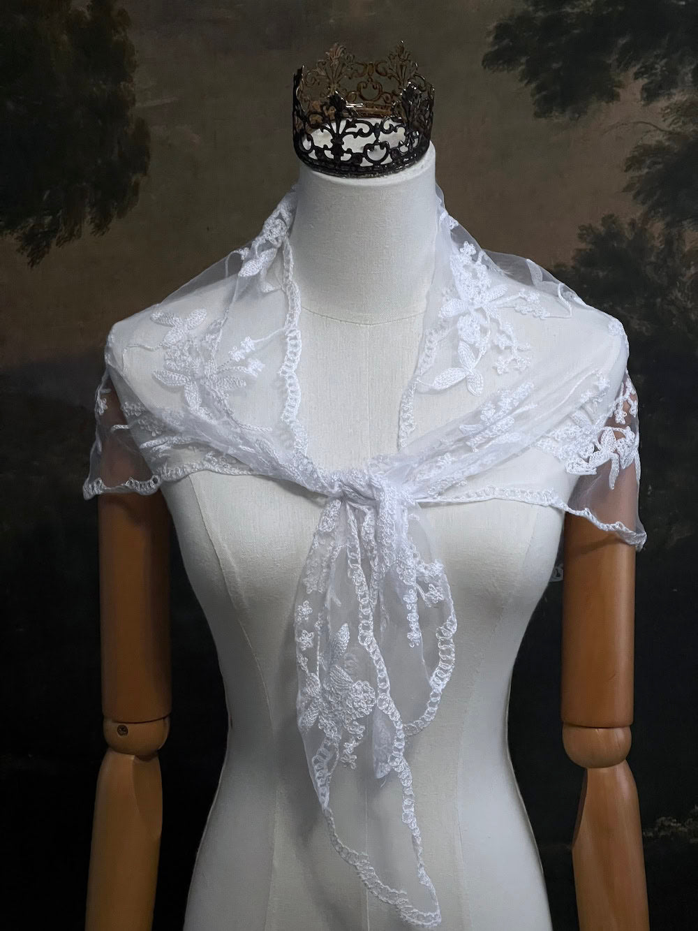 Mannequin wearing a vintage style white lace headscarf babushka triangle headdress made from floral embroidery lace as a shawl against an art history background