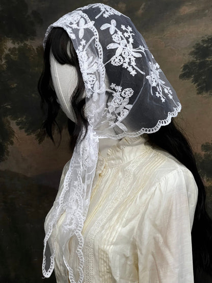 Mannequin wearing a vintage style white lace headscarf babushka triangle headdress made from floral embroidery lace against an art history background
