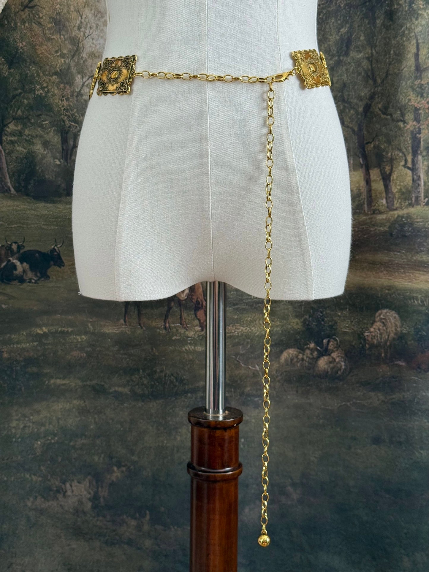 Historically inspired victorian era square concho style belt with rectangular gold toned metalwork, a scalloped edge, and floral motifs.