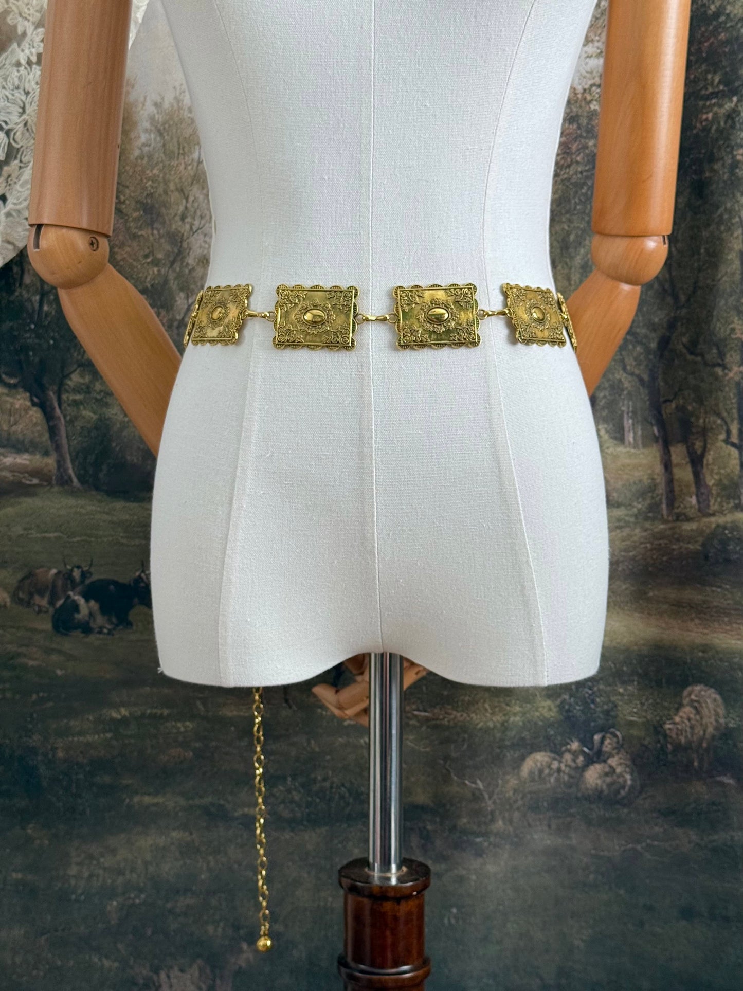 Historically inspired victorian era square concho style belt with rectangular gold toned metalwork, a scalloped edge, and floral motifs.