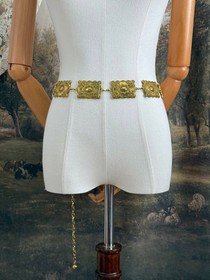 Historically inspired victorian era square concho style belt with rectangular gold toned metalwork, a scalloped edge, and floral motifs.