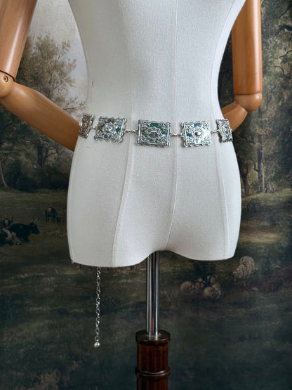 A silver concho style floral victorian metalwork rectangle chain belt pictured on a mannequin.
