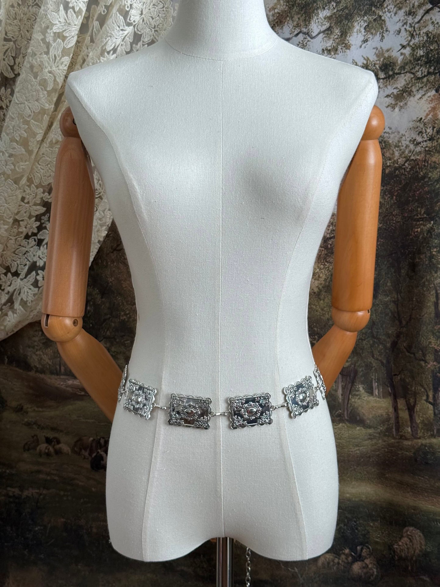 A silver concho style floral victorian metalwork rectangle chain belt pictured on a mannequin.