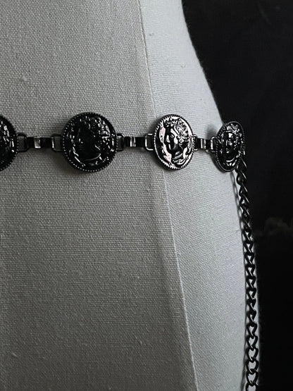A historically inspired renaissance and medieval metal cameo coin belt in dark charcoal metal on a mannequin.