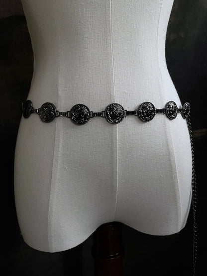 A historically inspired renaissance and medieval metal cameo coin belt in dark charcoal metal on a mannequin.