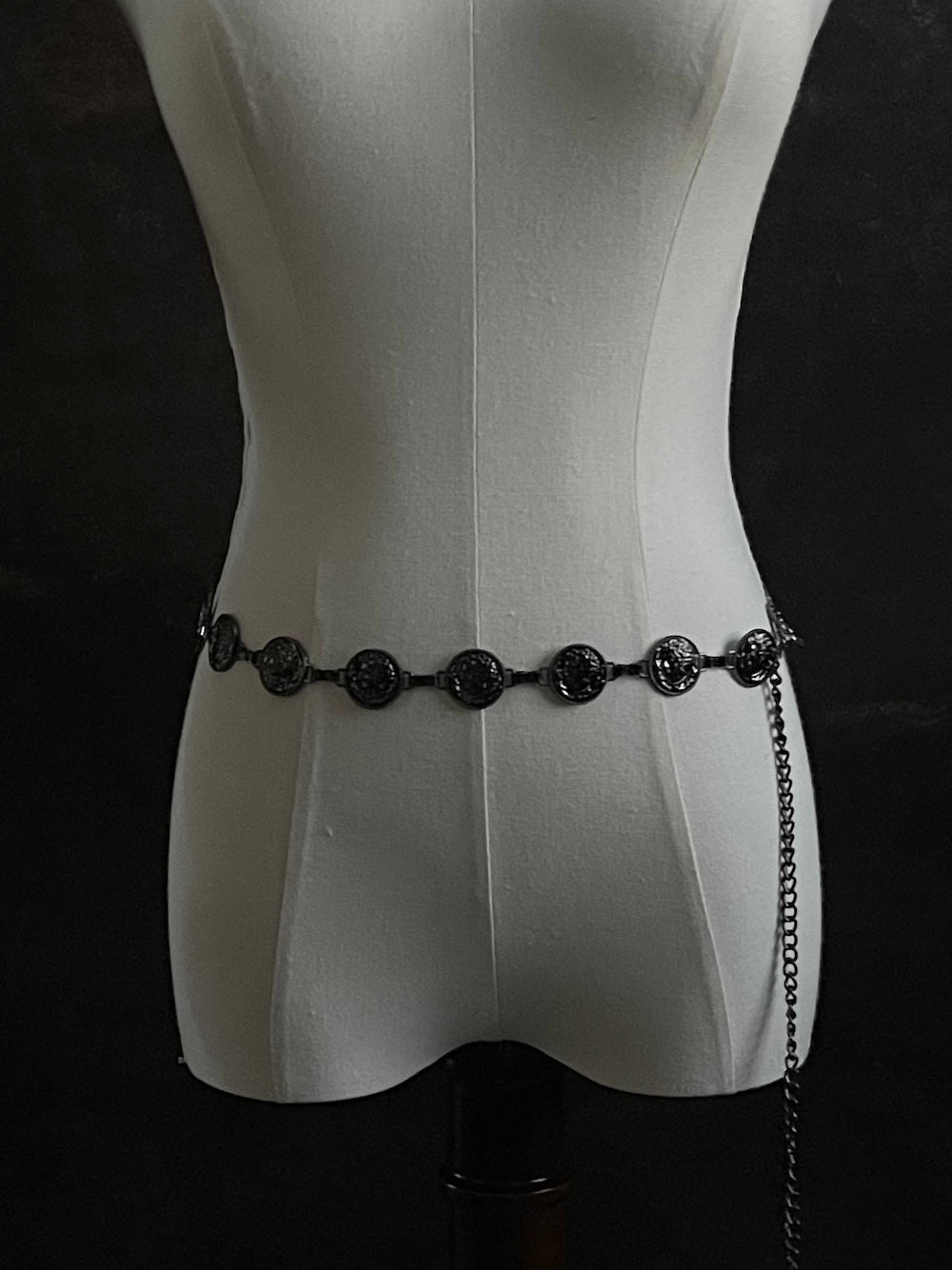 A historically inspired renaissance and medieval metal cameo coin belt in dark charcoal metal on a mannequin.