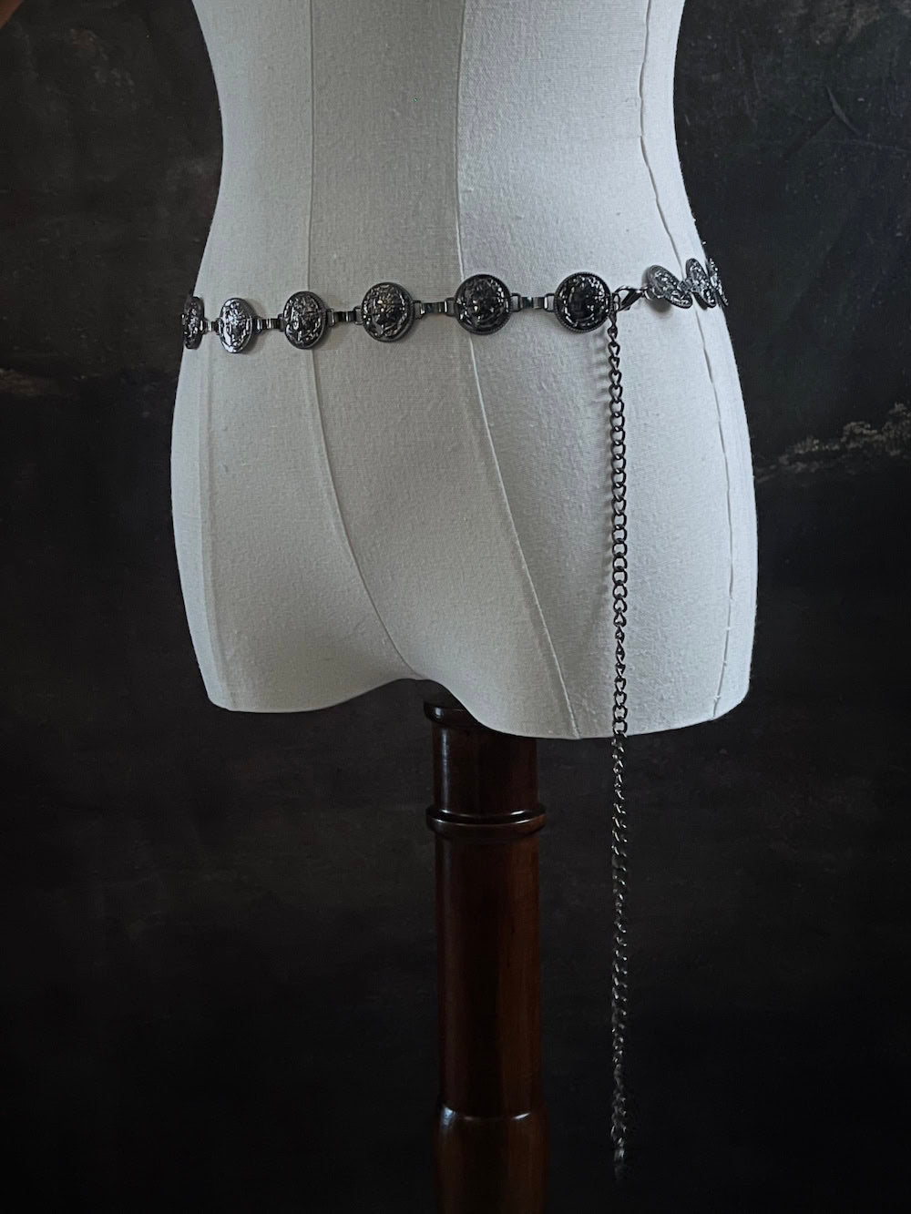 A historically inspired renaissance and medieval metal cameo coin belt in dark charcoal metal on a mannequin.