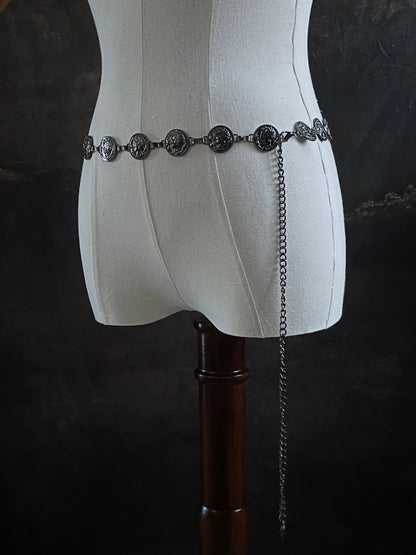 A historically inspired renaissance and medieval metal cameo coin belt in dark charcoal metal on a mannequin.