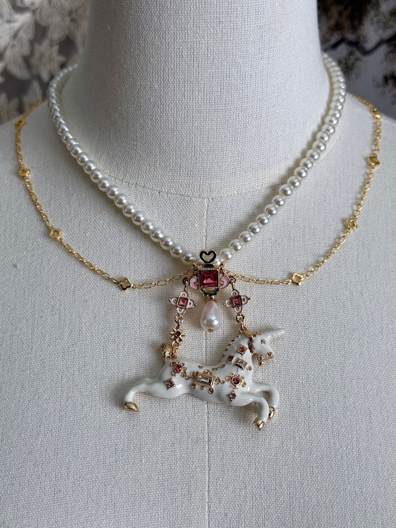 Handmade historical jewelry inspired pearl and chain necklace with a bejeweled medieval unicorn pendant, displayed on a mannequin.