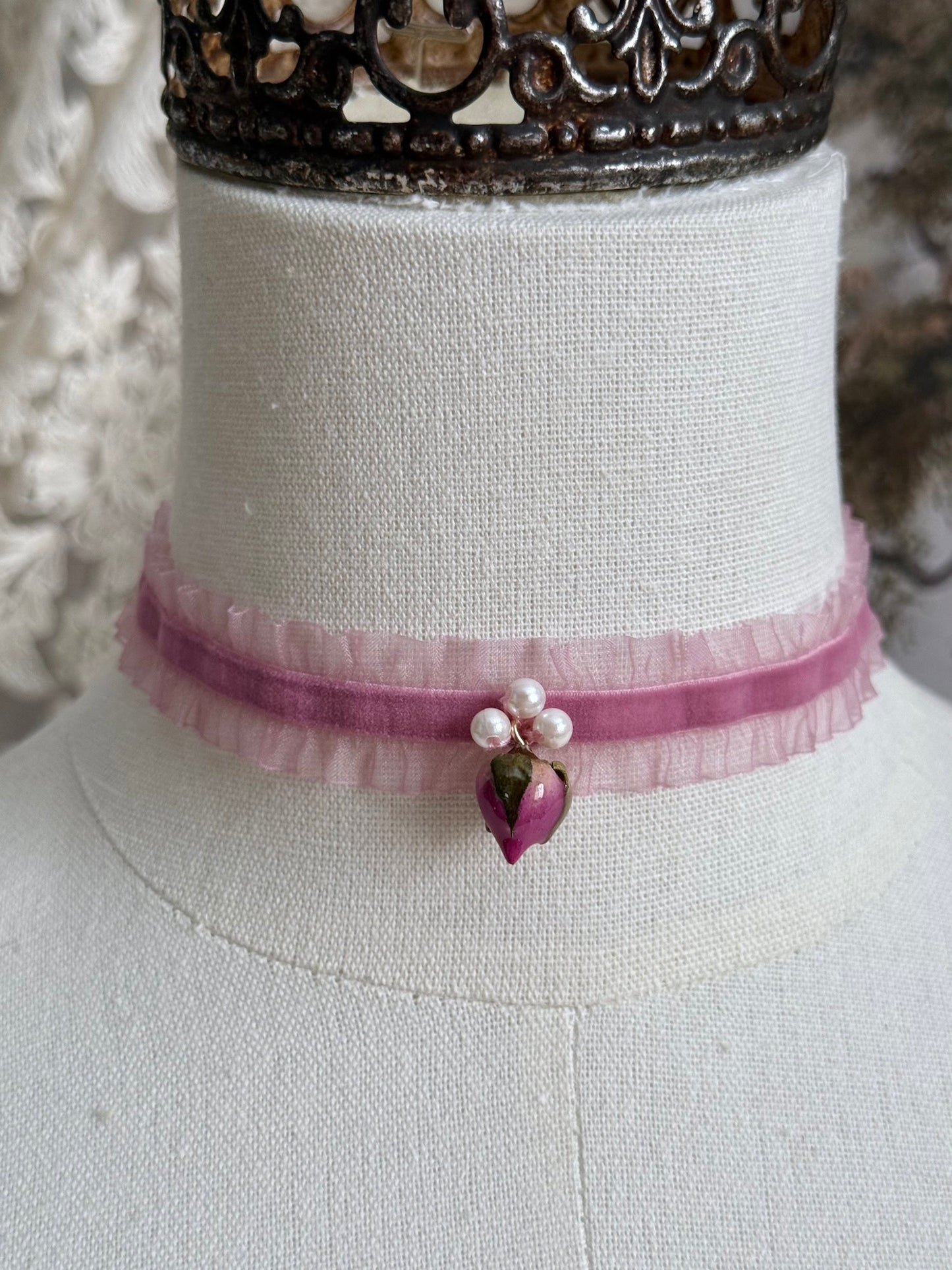 A victorian fashion inspired mauve pink velveteen and chiffon ruffle lace choker necklace with a real rose bud charm and three faux pearl beads pictured on a mannequin
