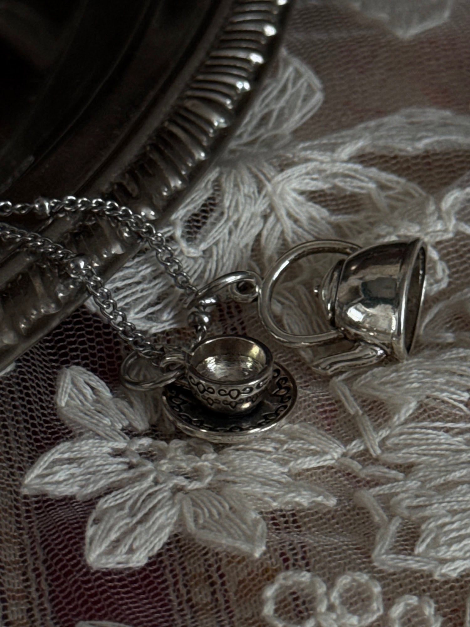 A victorian inspired teapot and teacup pendant necklace in silver.