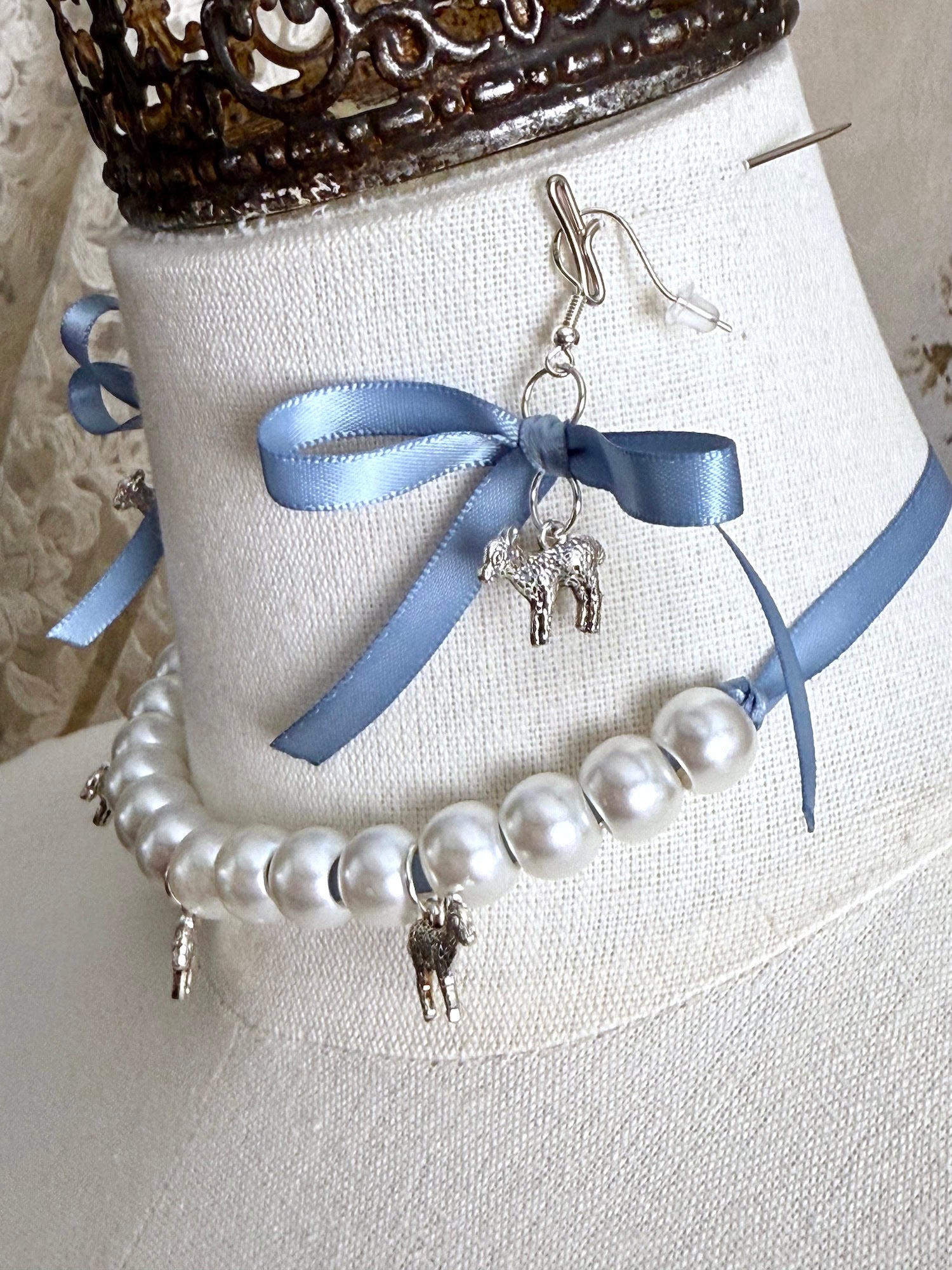 A vintage inspired handmade set of jewelry (earrings and necklace) featuring faux pearl beads, silver lamb charms,  and pastel blue ribbon bows.