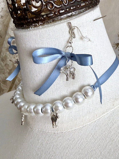 A vintage inspired handmade set of jewelry (earrings and necklace) featuring faux pearl beads, silver lamb charms,  and pastel blue ribbon bows.