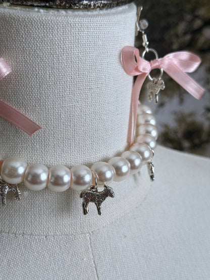A vintage inspired handmade set of jewelry (earrings and necklace) featuring faux pearl beads, silver lamb charms,  and pastel pink ribbon bows.