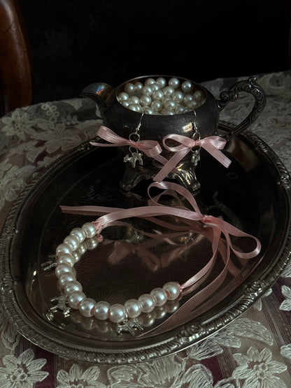 A vintage inspired handmade set of jewelry (earrings and necklace) featuring faux pearl beads, silver lamb charms,  and pastel pink ribbon bows.