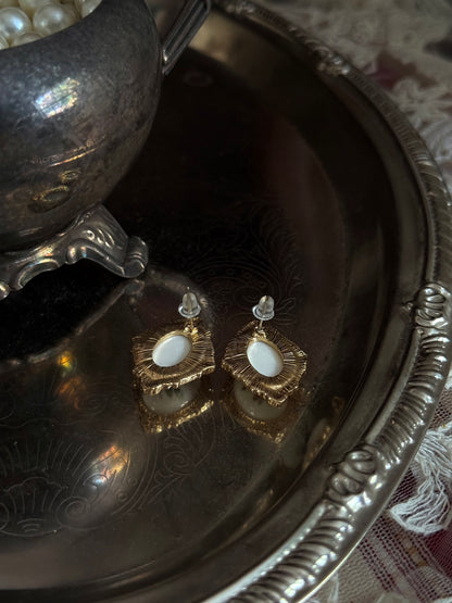 Pair of Historically-Inspired Painted Rose Ceramic gold-framed earrings displayed on an antique silver dish