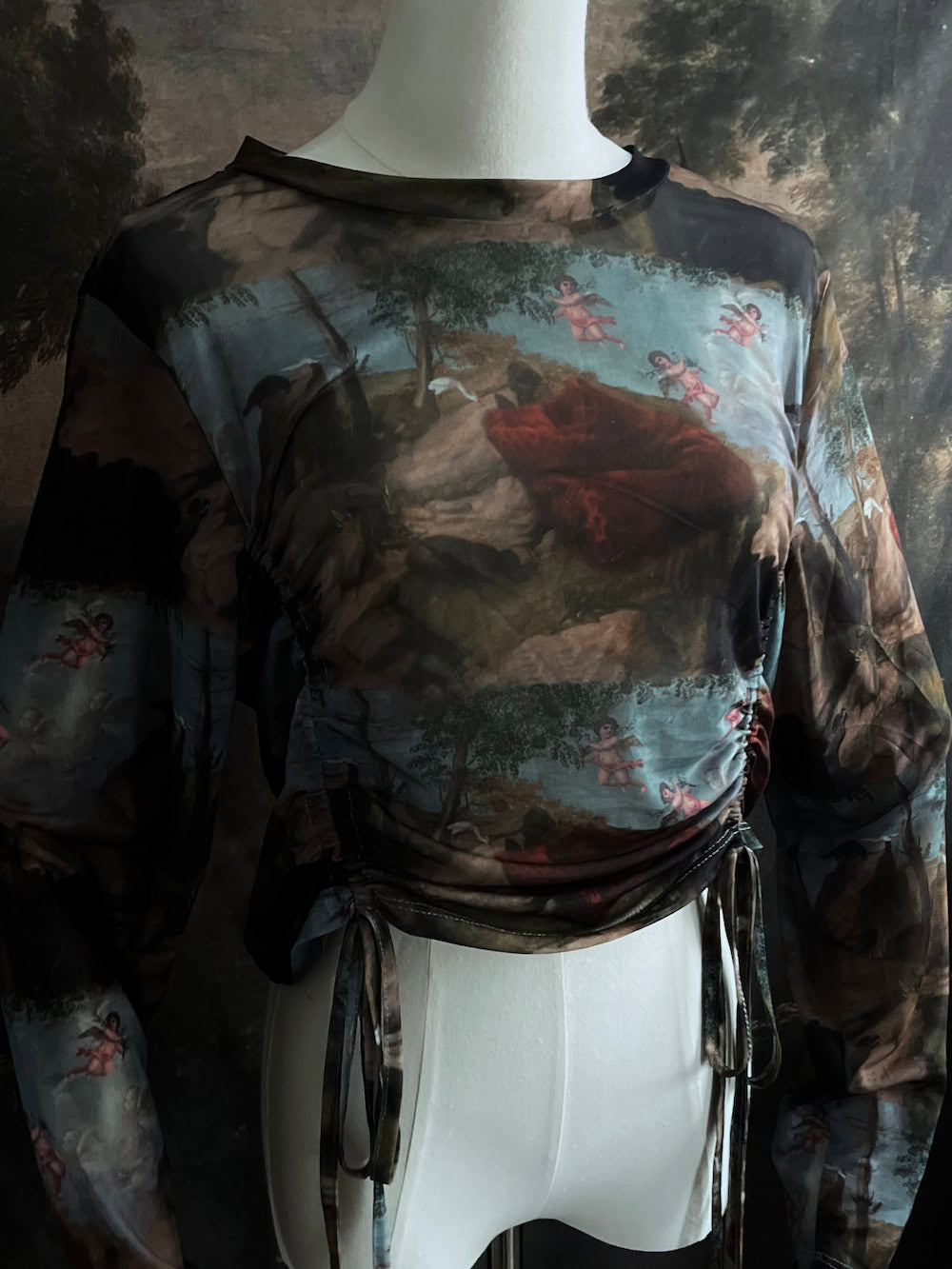 A Historical Renaissance Painting Printed Sheer Mesh Long-Sleeve Ruched Blouse on a mannequin in front of an art history backdrop