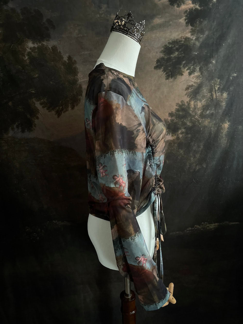 A Historical Renaissance Painting Printed Sheer Mesh Long-Sleeve Ruched Blouse on a mannequin in front of an art history backdrop