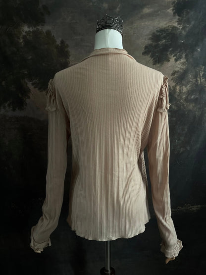 A Beige / light brown Victorian Inspired Ribbed Knit Long-Sleeve Top with ribbon Bow Applique and ruffle trim in front of an art history painting backdrop