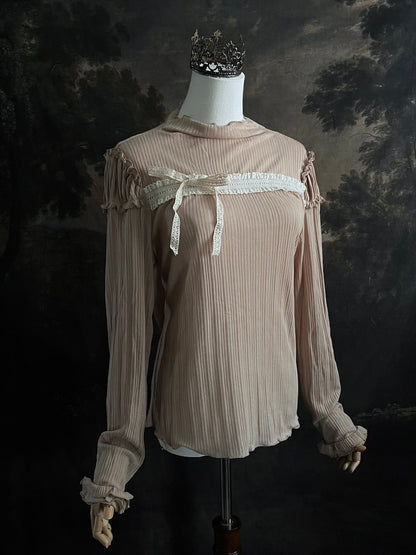 A Beige / light brown Victorian Inspired Ribbed Knit Long-Sleeve Top with ribbon Bow Applique and ruffle trim in front of an art history painting backdrop