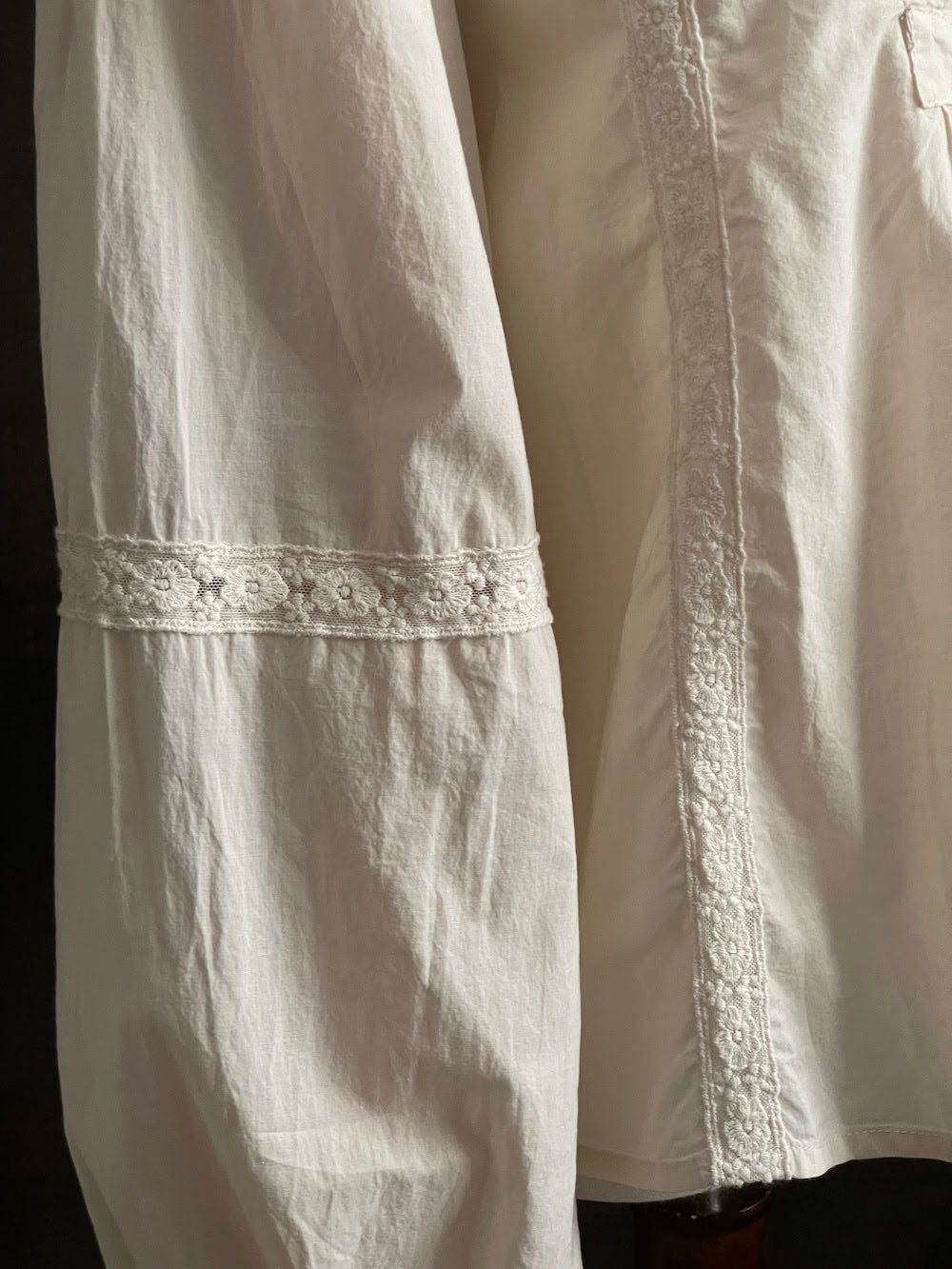 A historically inspired regency and victorian style high neck beige cotton blouse with bishop sleeves and lace trim on a mannequin