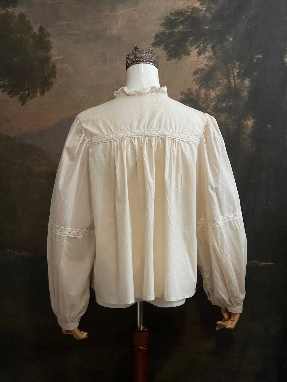 A historically inspired regency and victorian style high neck beige cotton blouse with bishop sleeves and lace trim on a mannequin