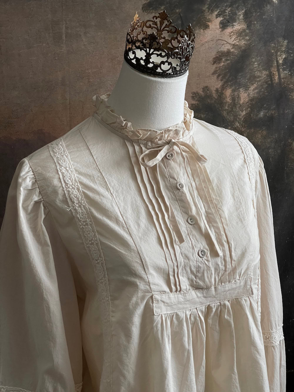 A historically inspired regency and victorian style high neck beige cotton blouse with bishop sleeves and lace trim on a mannequin