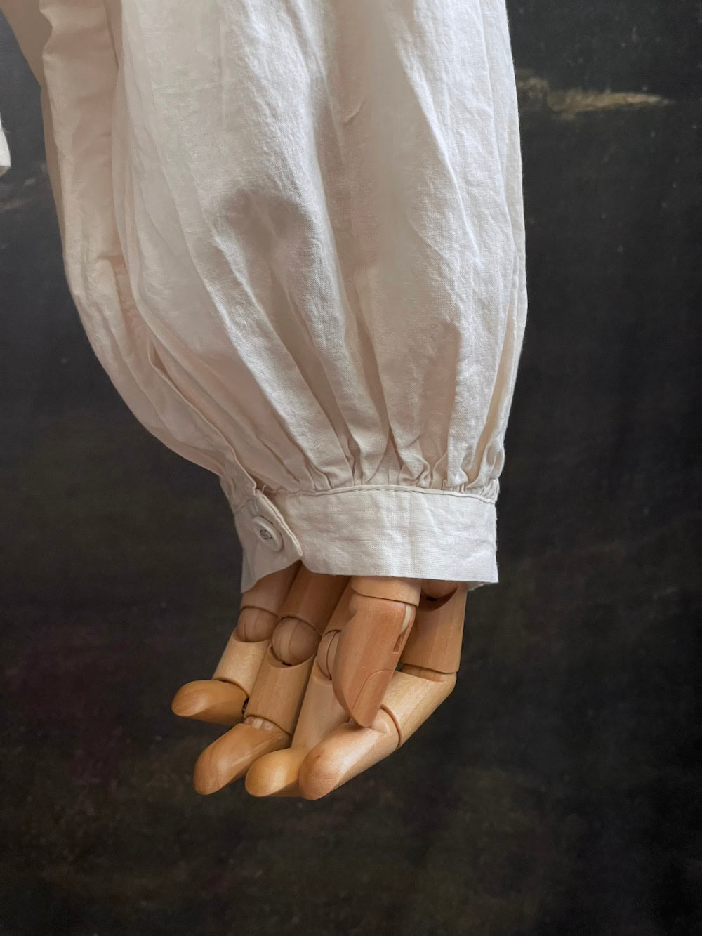 A historically inspired regency and victorian style high neck beige cotton blouse with bishop sleeves and lace trim on a mannequin