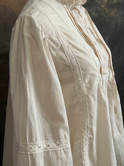 A historically inspired regency and victorian style high neck beige cotton blouse with bishop sleeves and lace trim on a mannequin