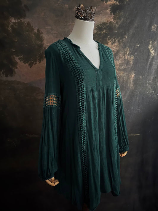 A historical fantasy inspired dark green bohemian medieval revival style dress on a mannequin in front of an art history backdrop