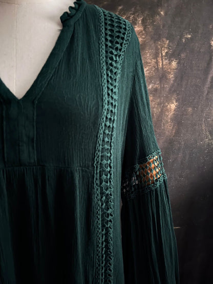 A historical fantasy inspired dark green bohemian medieval revival style dress on a mannequin in front of an art history backdrop