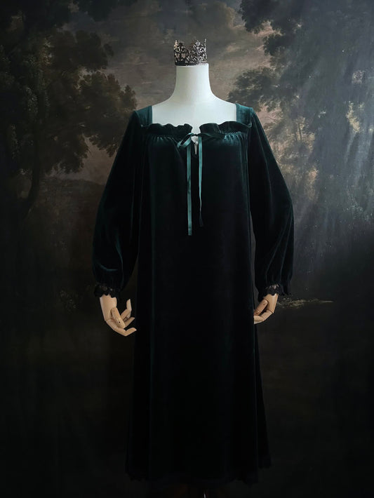 A dark forest emerald green velour velvet square neckline long sleeve midi dress with black floral lace trim and a satin drawstring on an art history backdrop