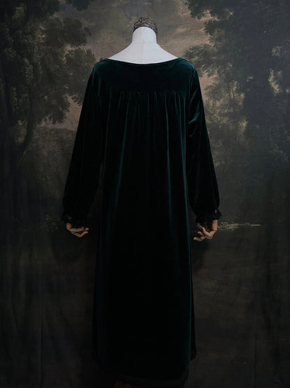 A dark forest emerald green velour velvet square neckline long sleeve midi dress with black floral lace trim and a satin drawstring on an art history backdrop