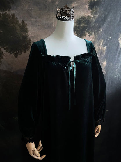 A dark forest emerald green velour velvet square neckline long sleeve midi dress with black floral lace trim and a satin drawstring on an art history backdrop