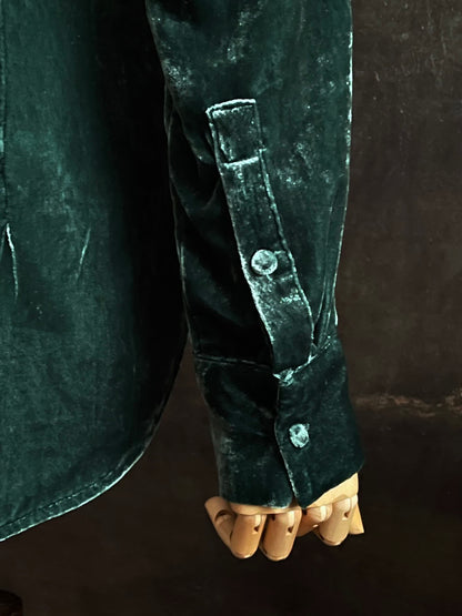 Mannequin wearing a dark green velvet button up vintage medieval revival style collared shirt against a dark, forest-themed art history background