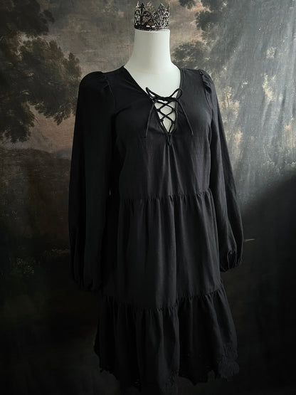 Historically inspired witchy gothic black tiered mini dress with corset lace up bodice and long bishop sleeves on a mannequin in front of a dark art history backdrop