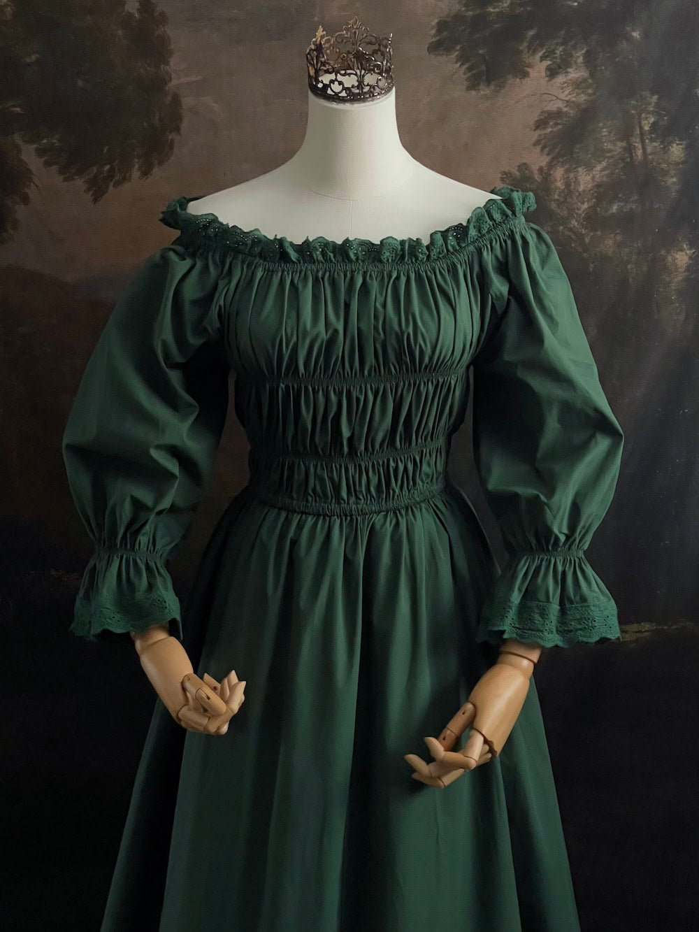 Dark Forest Green historical fashion inspired shirred chemise maxi dress gown with lace trim and bell sleeves on a mannequin against a dark forest background