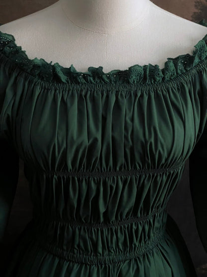 Dark Forest Green historical fashion inspired shirred chemise maxi dress gown with lace trim and bell sleeves on a mannequin against a dark forest background