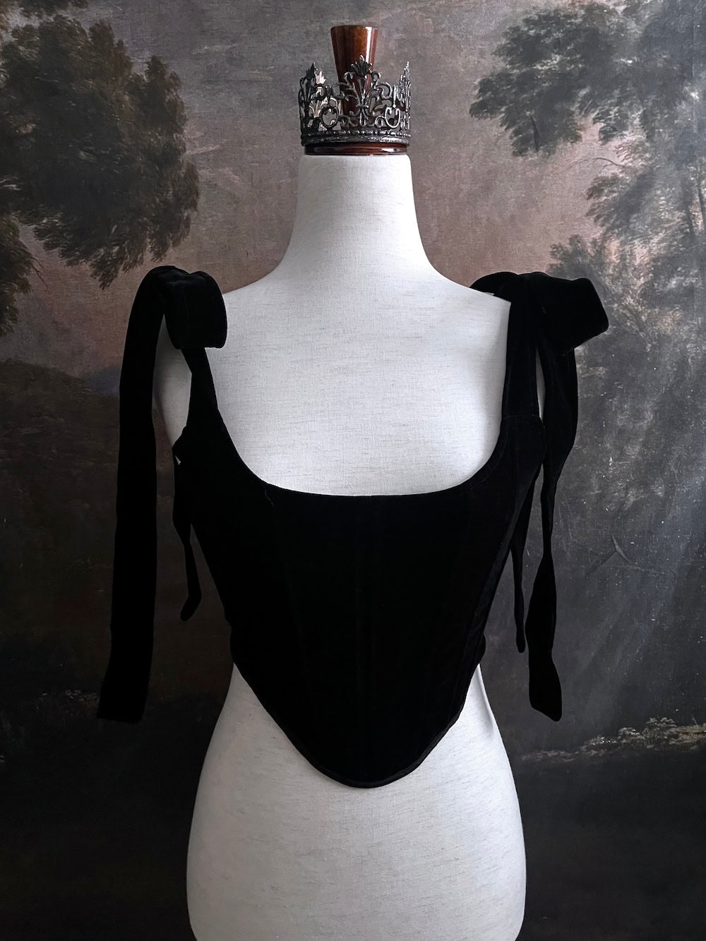 A pair of historical fashion inspired renaissance and baroque era gothic black velvet corset stays with bow straps, a basque waist, and a square neckline.