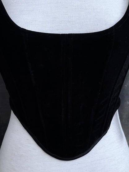 A pair of historical fashion inspired renaissance and baroque era gothic black velvet corset stays with bow straps, a basque waist, and a square neckline.