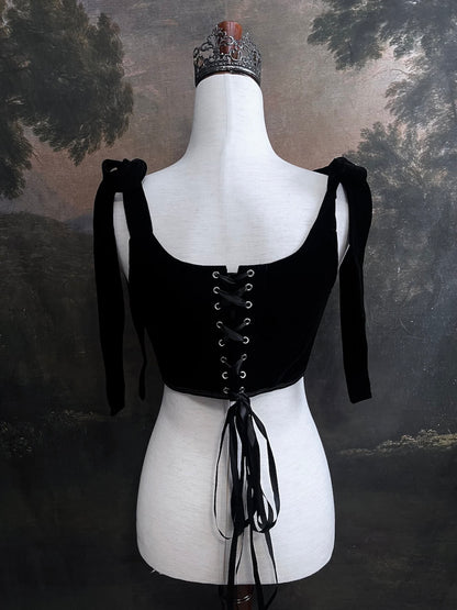 A pair of historical fashion inspired renaissance and baroque era gothic black velvet corset stays with bow straps, a basque waist, and a square neckline.
