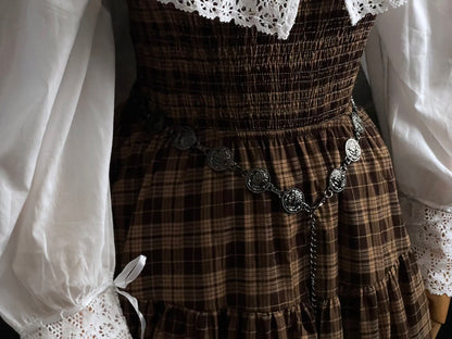 A historically inspired renaissance and medieval metal cameo coin belt in dark charcoal metal on a mannequin wearing a brown plaid dress.