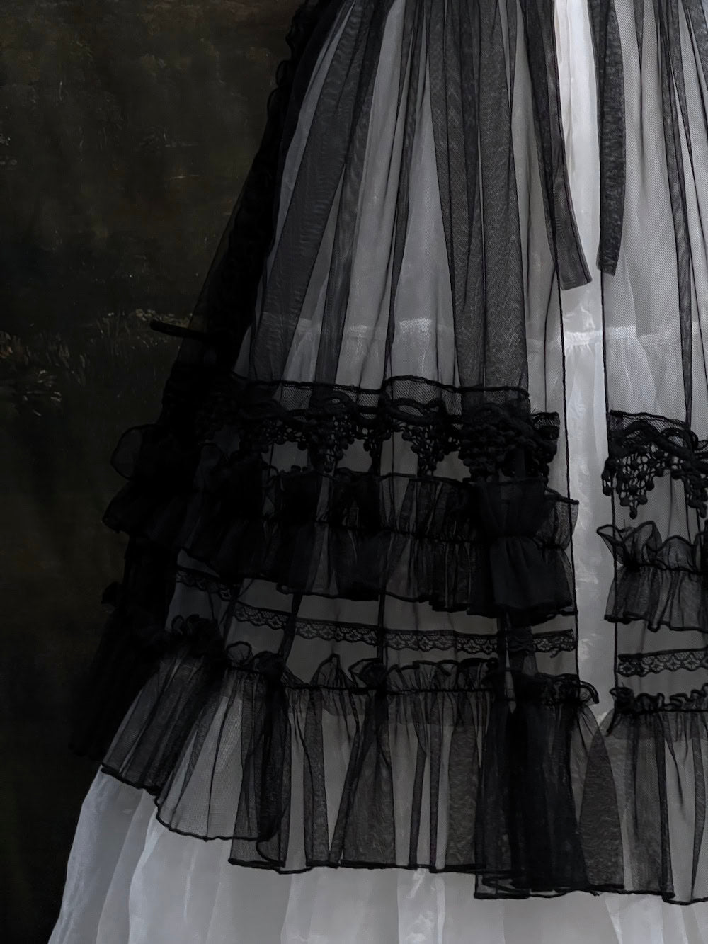 A versatile historically inspired overskirt and cape with lace trim and ruffle details in gothic black