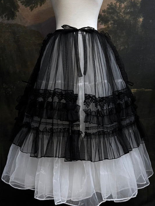 A versatile historically inspired overskirt and cape with lace trim and ruffle details in gothic black