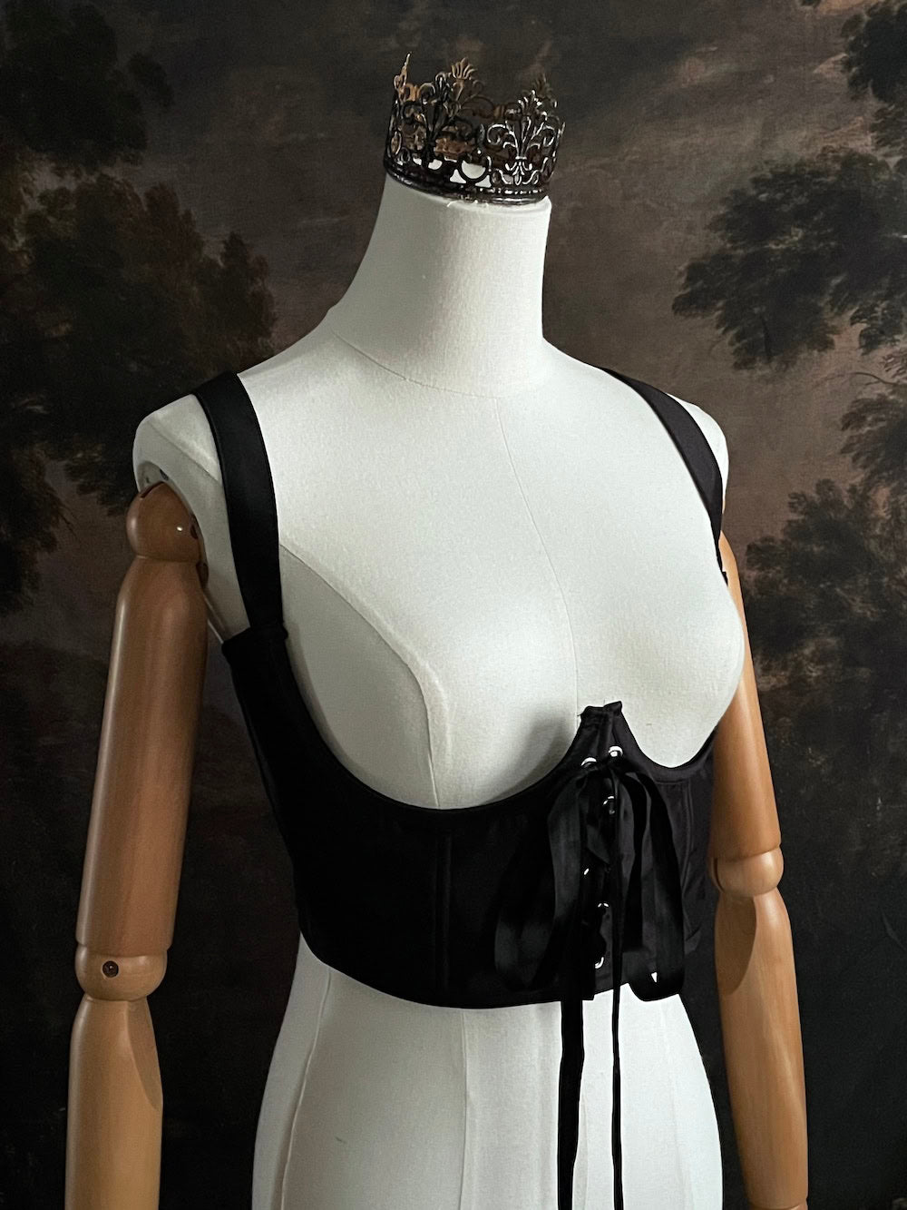 Black fantasy inspired underbust satin corset belt on a mannequin in front og an art history backdrop