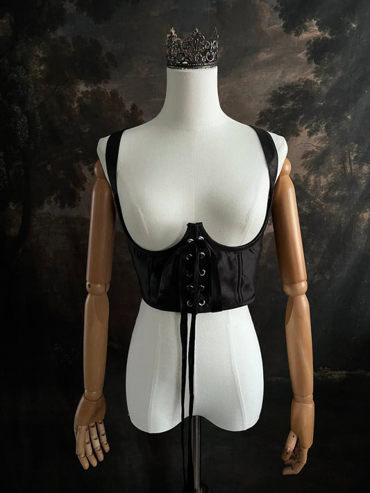 Black fantasy inspired underbust satin corset belt on a mannequin in front og an art history backdrop
