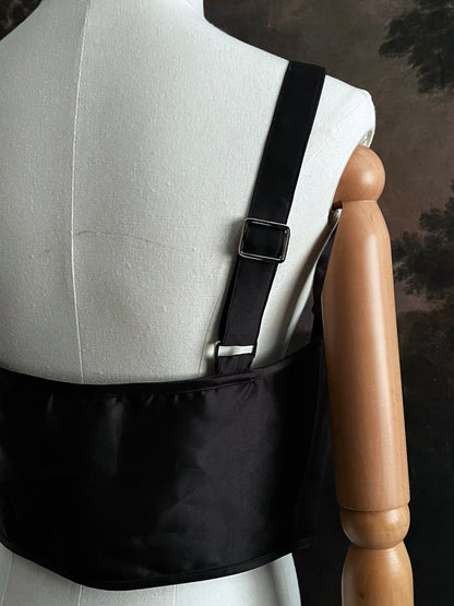 Black fantasy inspired underbust satin corset belt on a mannequin in front og an art history backdrop