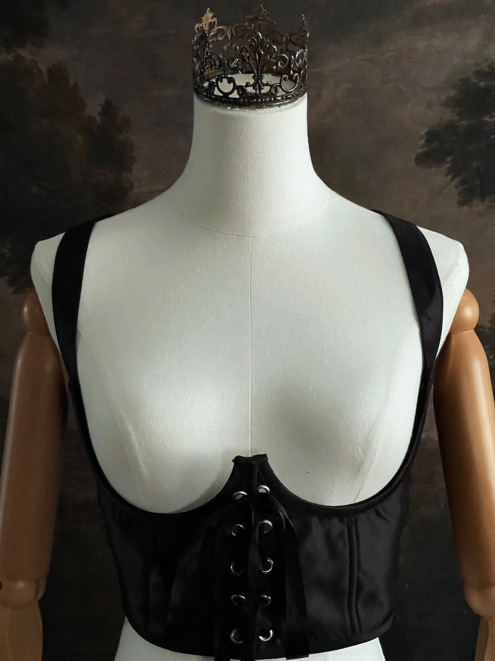 Black fantasy inspired underbust satin corset belt on a mannequin in front og an art history backdrop